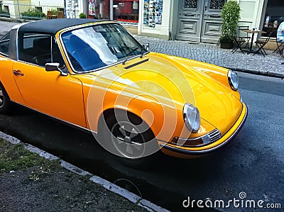 Old yellow sports car with a black roof, parked on a main street. Concept of power, power and wealth Editorial Stock Photo