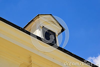 old yellow stucco roof dormer with small wood window. sloped clay tile roof . metal flashing trimmed edges Stock Photo