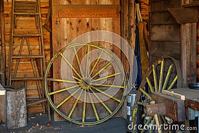 Old yellow wagon wheel waiting for restoration in an old barn Stock Photo