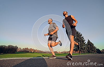 The old and young sportsmen running on the alley. Stock Photo