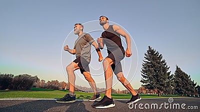 The old and young sportsmen running on the alley. Stock Photo