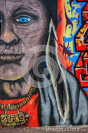 Older, aged American Indian with necklace and feather colourful graffiti mural on the wall Editorial Stock Photo