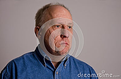 Older Bald Guy in Blue Denim Shirt Serious to Left Stock Photo