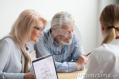 Older couple reading contract at meeting with real estate agent Stock Photo