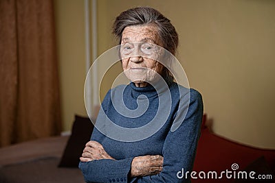 Older cute woman of ninety years old Caucasian with gray hair and wrinkled face looks at camera, cute kind look and smiles.Mature Stock Photo