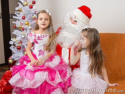 The older girl is sitting on lap of Santa Claus and tells poem Stock Photo