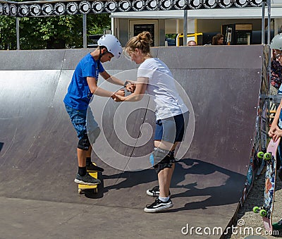 Older girl teach younger boy how to ride a skateboard. Skateboard lesson Editorial Stock Photo