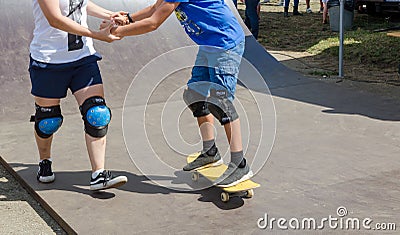 Older girl teach younger boy how to ride a skateboard. Skateboard lesson Editorial Stock Photo