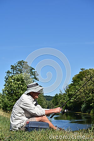 Older Male Fisherman Sitting With Rod And Reel Outdoors Stock Photo