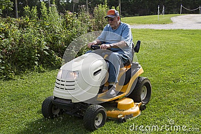 Older Male Mowing Grass With His Riding Mower Stock Photo