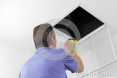 Man Inspecting an Air Duct with a Flashlight Stock Photo