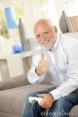 Older man giving thumb up with computer game Stock Photo