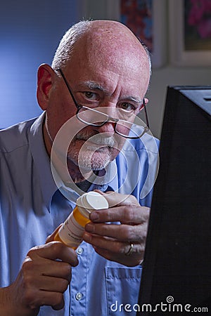 Older man look at camera and refilling prescription online, vertical Stock Photo