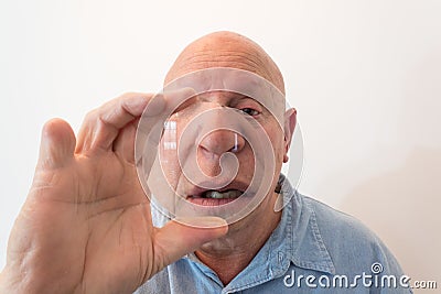 Older man looking over a large lens, distortion, bald, alopecia, chemotherapy, cancer, on white Stock Photo