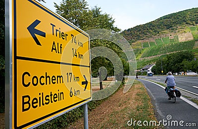 Male cyclist traveling along the bike path on the Mosel River in Germany with large traffic sign. Editorial Stock Photo