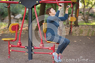 Older man working out on the sports public equipment in the outdoor gym. Stock Photo