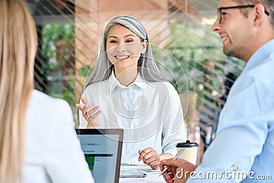 Older mature Asian manager talking to group of younger colleagues interns. Stock Photo