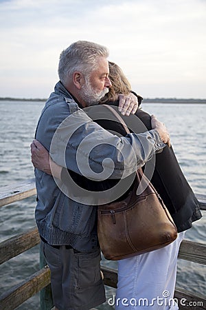 Older Middle-Aged Couple Hugging on Dock Stock Photo