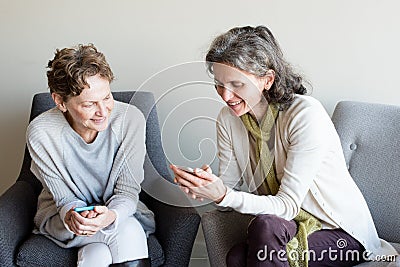 Older mother and daughter smiling with smartphones Stock Photo