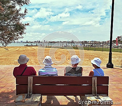 Older people facing the sea sit on bench Editorial Stock Photo