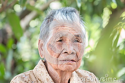 Older people for insurance concept : Portrait of Asian elder woman sitting alone with her black tooth at outdoor in sunny day Stock Photo