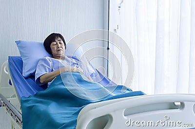 Older sick woman patient lay on bed in hospital with intravenous Stock Photo