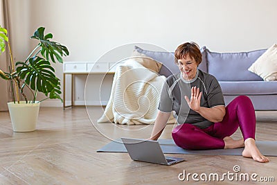 An older woman communicates with a trainer online before a Pilates workout. Stock Photo