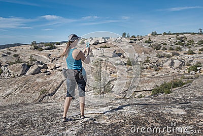 Woman hiker using phone to take pictures of rugged view Stock Photo