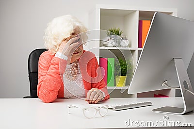 Older woman at the office having headache Stock Photo