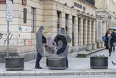 Older woman talking to two policeman in the street with pedestrians in the background. Editorial Stock Photo