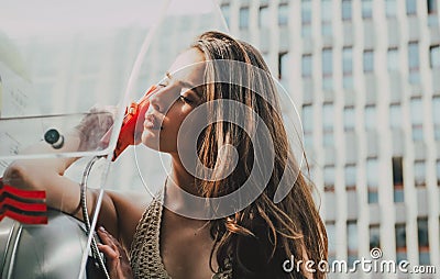 Oldfashion town. Woman with payphone. Vintage concept. Communication. Oldstyled city. Stock Photo