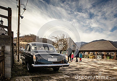 Oldtimer car Volga GAZ-21 built in a soviet Russia in traditional retro village Editorial Stock Photo