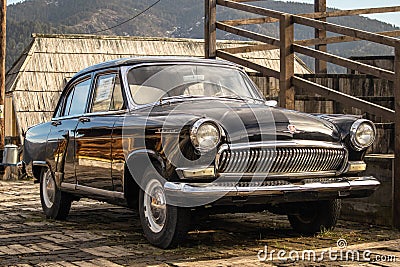 Oldtimer car Volga GAZ-21 built in a soviet Russia in traditional retro village Editorial Stock Photo