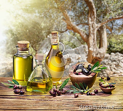 Olive berries in the wooden bowl and bottles of olive oil on the Stock Photo