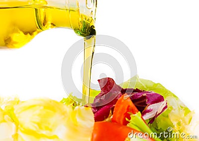 Olive oil bottle pouring in the Italian fresh salad on white Stock Photo