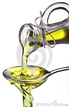 Olive oil flowing from carafe into the spoon. Stock Photo