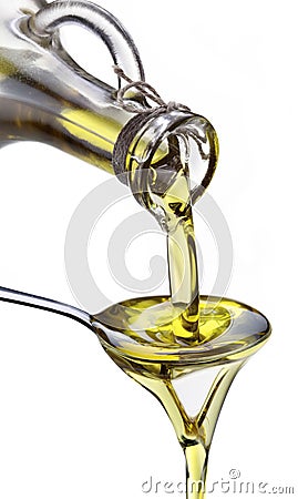 Olive oil flowing from carafe into the spoon. Stock Photo