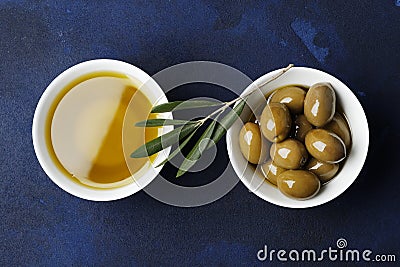 Olive oil and green olives on a blue background. Stock Photo