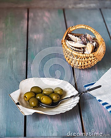 Olives in a flat sink and a wicker basket with sea shells, marine-themed paper napkins Stock Photo