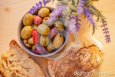 Olives stuffed, red pepper and homemade bread. Multicolored olives in a small bowl on a wooden table. Stock Photo