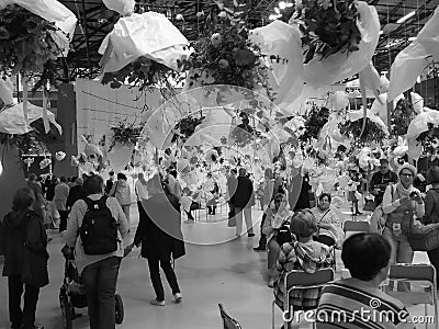 Greyscaled image - Multiple bouquets in white paper hanging from the ceiling over people in a hall of Flora Exposition Editorial Stock Photo