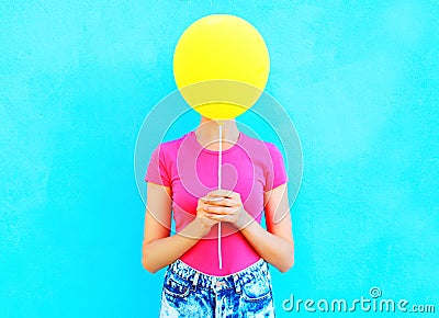 Ð¡olorful woman hiding face yellow air balloon having fun over blue Stock Photo