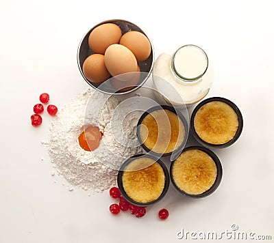 Still life with flour, eggs, currants a bottle of milk and four custards in their molds Stock Photo