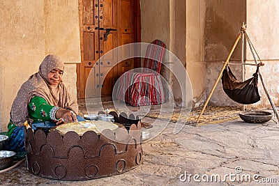 Omani woman in traditional dress preparing a crispy crepe in Nizwa fort Editorial Stock Photo
