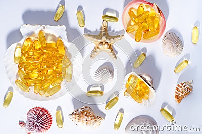 Omega 3 capsules and seashells with long shadows. Top view photo of supplement food with oil of nordic fish. Vitamins and tablets Stock Photo