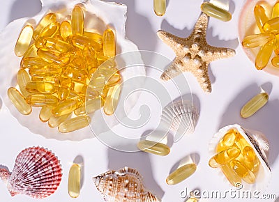 Omega 3 capsules and seashells with long shadows. Top view photo of supplement food with oil of nordic fish. Vitamins and tablets Stock Photo