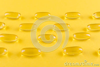 Golden omega capsules on yellow background closeup Stock Photo