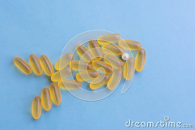 Omega 3 chewable jelly pills shaped as fish with pearl eye. Capsules with yellow fish oil are lying on blue background Stock Photo