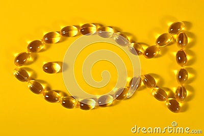 Omega-3 fish fat oil capsules shaped in fish on a yellow Stock Photo