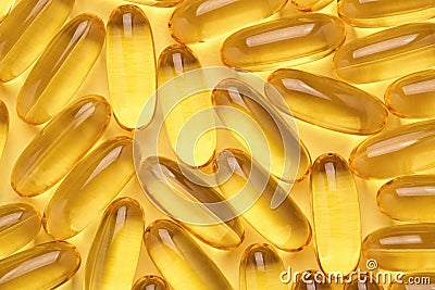 Omega 3 softgels or Fish oil capsules, yellow pills background. Stock Photo